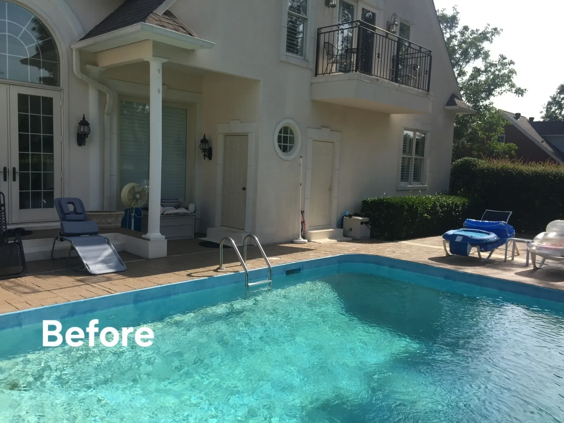 Backyard swimming pool area before renovation with lounge chairs and house exterior.