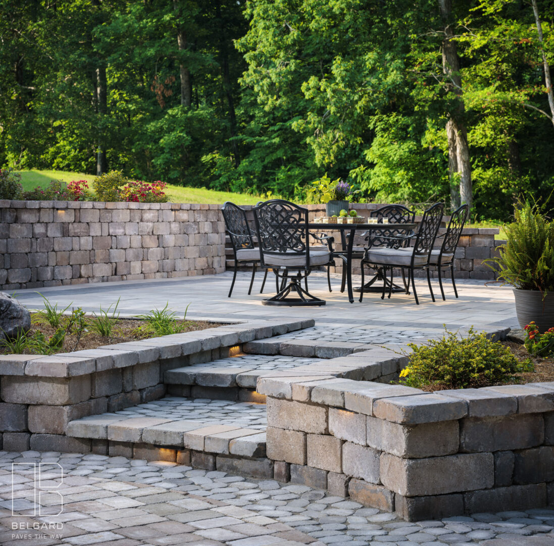 Outdoor stone patio with black metal chairs and table.